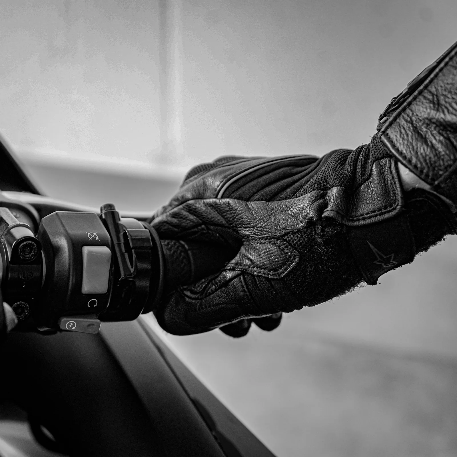 Mains gantées de gants ventilés bleus sur le guidon d’une moto